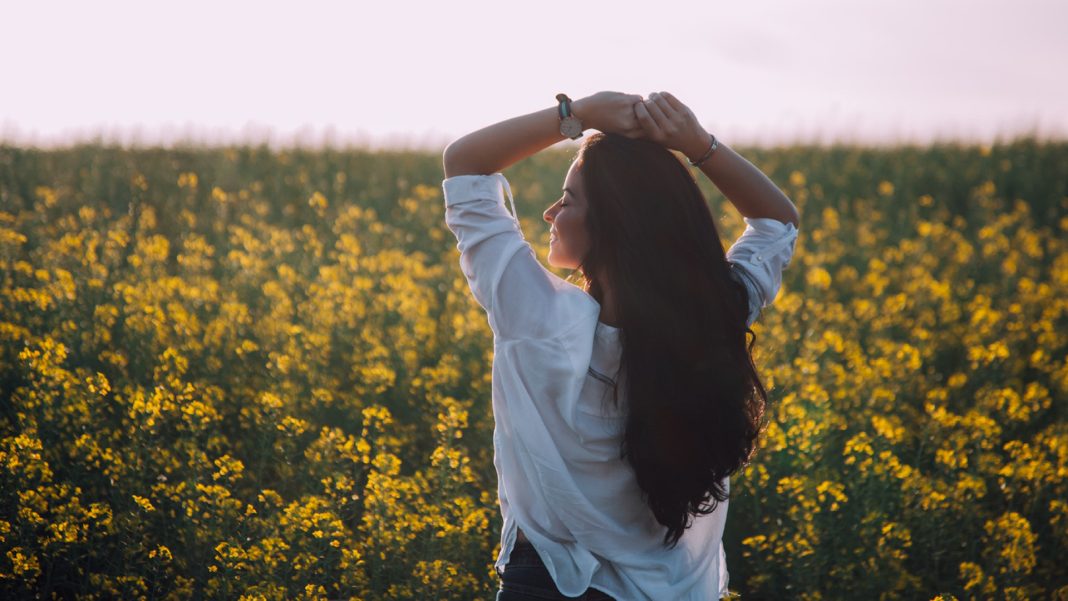 Woman holding arms over her head in a field